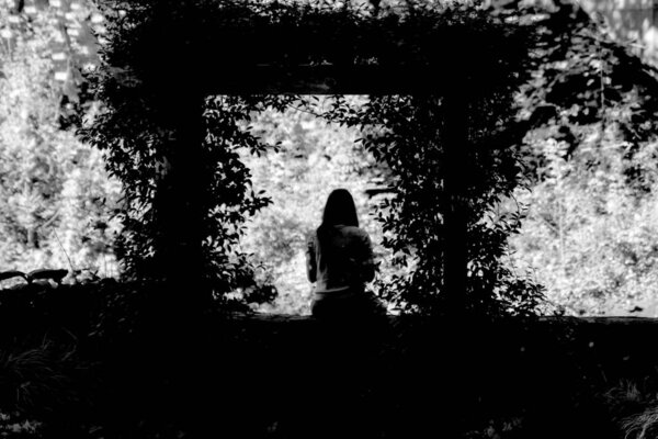 Silhoutted woman sitting under an arbor