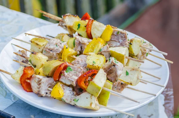 Espetos saborosos de peixe fresco com legumes e maçãs em um prato de carne shish de madeira Imagem De Stock