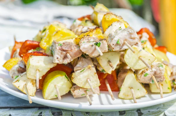 Leckere Spieße aus frischem Fisch mit Gemüse und Äpfeln auf einem hölzernen Dönerspieß Stockbild