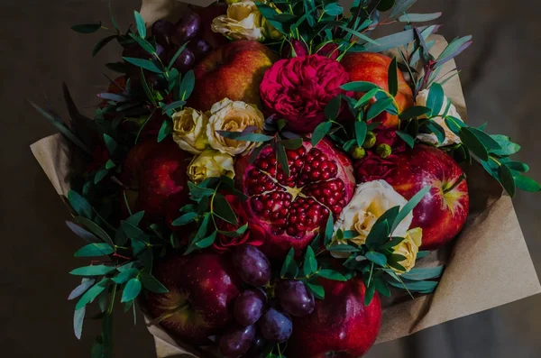 Frischer Herbst vegetarischer fruchtiger Strauß von Äpfeln, Trauben, Granatäpfeln und Rosen Stockfoto