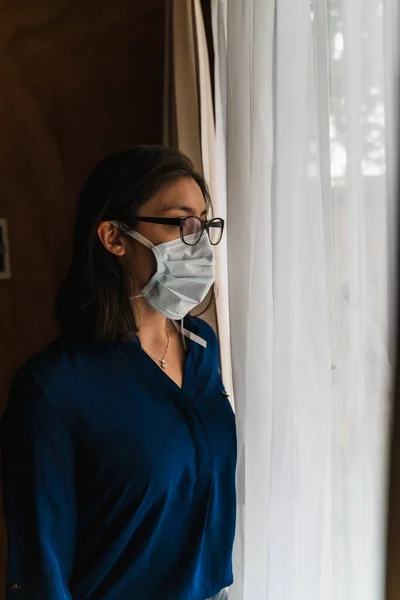 woman with face mask looking out the window