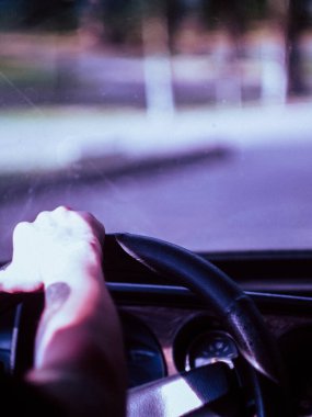 Avrupa 'da eski bir arabanın direksiyonuna dövmeli bir erkek eli yakın çekimde, direksiyon solda.