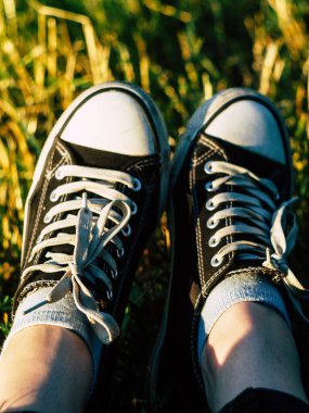 Parktaki çimlerin üzerinde spor ayakkabı giymiş güzel bir kadın.