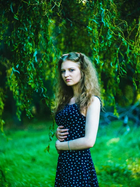 Beautiful blonde girl in a dress on a background of a summer green field — Stock Photo, Image