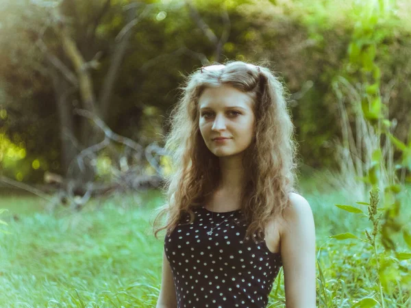 Mooi blond meisje in een jurk op een achtergrond van een zomer groen veld — Stockfoto