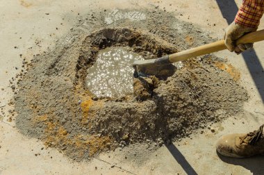 İşçi çapayla çimento karışımı yapıyor. Güneşli bir yaz gününde inşaatta çalışan bir adam. Açık hava sahnesi.