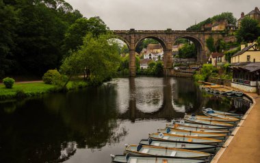 Nidd Nehri manzarası, eski köprü ve bulutlu bir günde Knaresborough Kalesi 'nin yıkıntılarından gelen kayıklar. İngiltere 'nin güzel köyü.