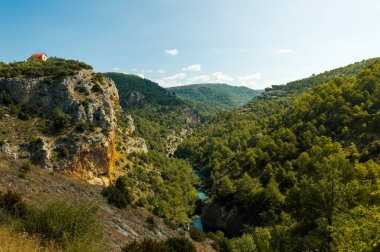 Cuenca, İspanya 'da Jucar nehrinin kıyısındaki bir uçurumda yalnız ve şirin bir evin güzel manzarası. Güneşli bir günde doğa manzarası.