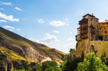 İspanya 'nın Cuenca kentindeki Asılan Evler (Casas Colgadas) ve dağların güneşli manzarası. Kayalıkların üzerine inşa edilmiş turistik evler..