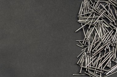 Siyah zemin üzerinde farklı metal çivi yığınları ve sol tarafında kopya alanı var. Marangozluk veya reform kavramına sahip karanlık bir zemin.