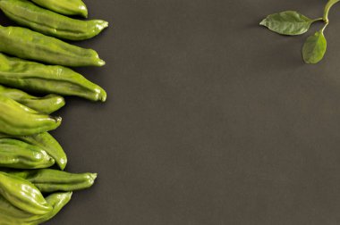 Siyah arka planda lezzetli yeşil biberli arka plan. Ortasında fotokopi alanı var. Taze ve organik sebzelerin üst görüntüsü.