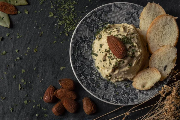 Maydanozlu badem humusu ve yayılacak ekmek. Baklagillerden yapılmış lezzetli bir yemeğin güzel sunumu. Kopyalama alanı olan arkaplan.