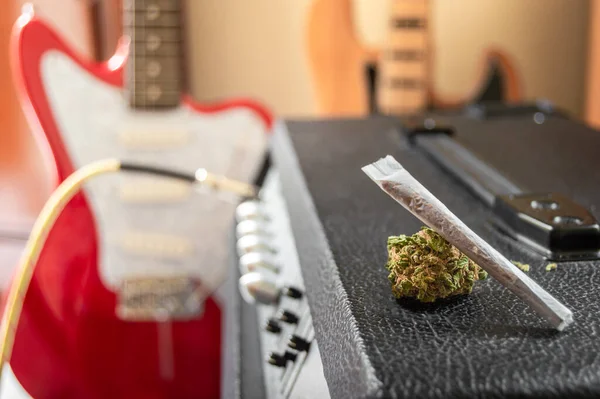 Müzik ve marihuana, ilham verici görünüyor. Ot ve büyük marihuana tomurcuğu hoparlörde. Arka planda bulanık efektli müzik aletleri.
