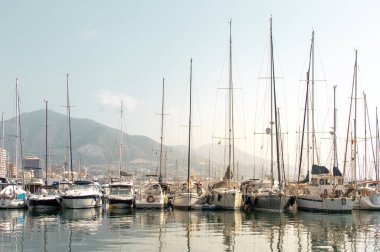 Rıhtımdaki yelkenli ve yatlar şehre ve arka plandaki dağlara yansıdı. Costa del Sol 'un (Fuengirola) manzarası, İspanya.