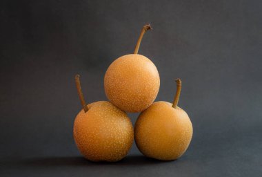 Taze Nashi ya da siyah zemin üzerinde izole edilmiş Asya armutları tarafından oluşturulan piramit. Pyrus Pyrifolia 'ya yakın, koyu arkaplanda nadir bulunan bir meyve türü..