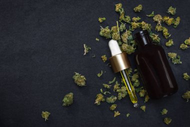 CBD yağı ya da tentür siyah arka planda esrar ve marihuana tomurcukları ile fotokopi alanı bırakılır. Terapötik marihuana ürünü.