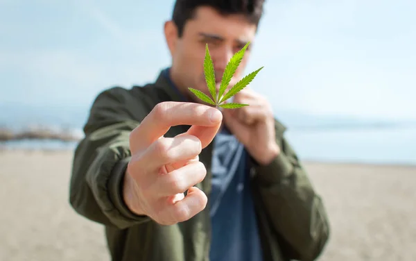 Ung Man Som Håller Ett Marijuanablad Och Röker Cannabis Stranden — Stockfoto