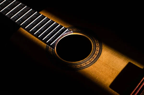 暗闇の中でのギターの抽象的な背景 太陽の光に照らされたギターの中央部 — ストック写真