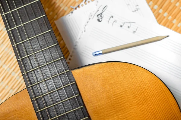 Top view of a classical guitar, music notebook with stave and pencil. Concept of composing or studying music.