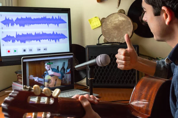 Genç adam evde gitar dersi kaydediyormuş. Müzisyen, teknoloji ve bilgisayarları kullanarak çevrimiçi video eğitimi yapıyor..
