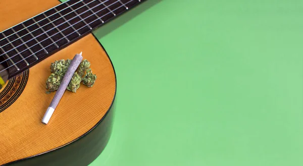 Büyük marihuana mekanı ve yeşil arka planda izole edilmiş gitarda esrar tomurcukları. Uzayı doğru kopyala. Müzik ve ot kavramı, ilham, yaratıcılık...
