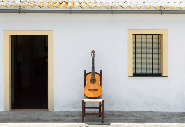 Güneşli bir günde, kırsalda güzel bir evin beyaz cephesinin önündeki İspanyol gitarı. Flamenko ya da Endülüs konsepti.