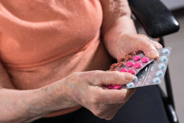Starší žena držící různé léky balíček — Stock fotografie