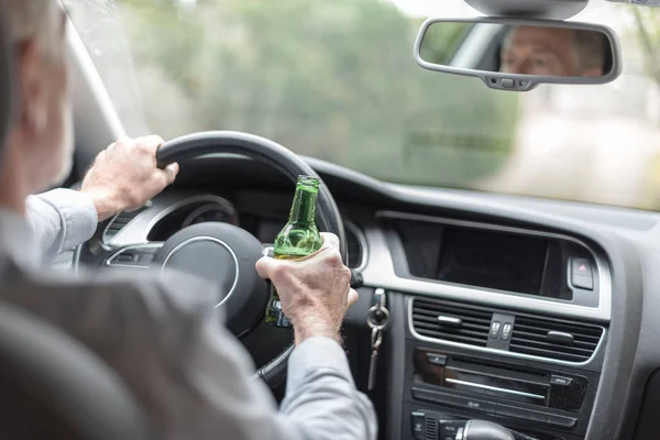 Hombre sosteniendo una botella de cerveza y conduciendo — Foto de Stock