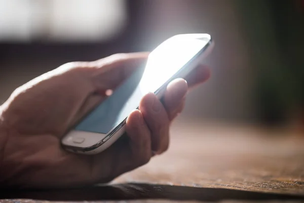 Hand holding a phone, hard light and blurred effect — Stock Photo, Image