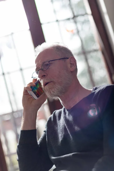 Senior man talking on phone, hard light and flare effect — Stock Photo, Image