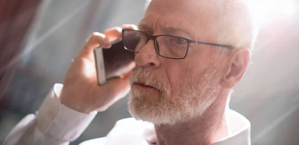 Старший бизнесмен разговаривает по мобильному телефону, световой эффект — стоковое фото