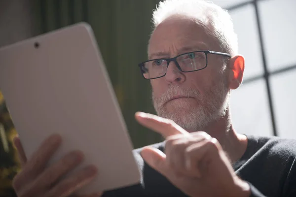Senior man using his tablet, hard light effect — Stock Photo, Image