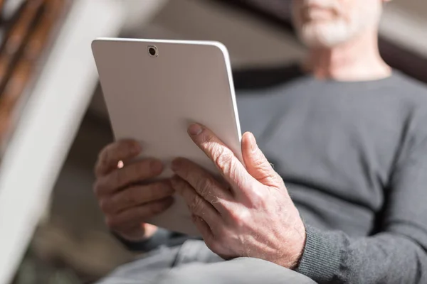 Senior man met zijn tablet, harde lichteffect — Stockfoto