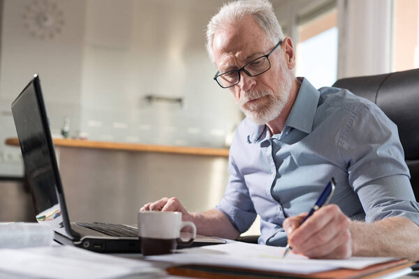 Senior businessman taking notes, hard light