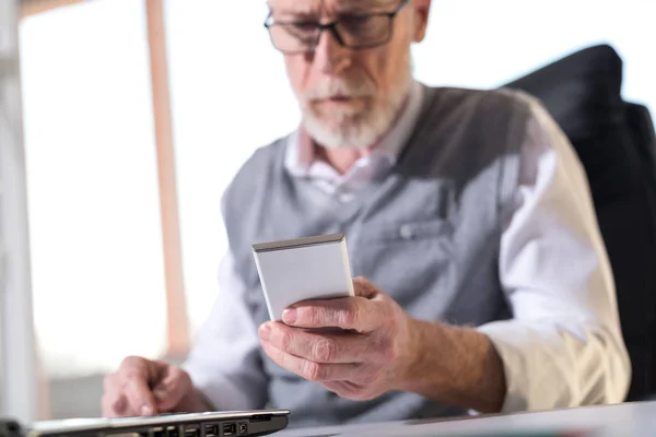 Senior zakenman lezen van een bericht op zijn mobiele telefoon, harde l — Stockfoto