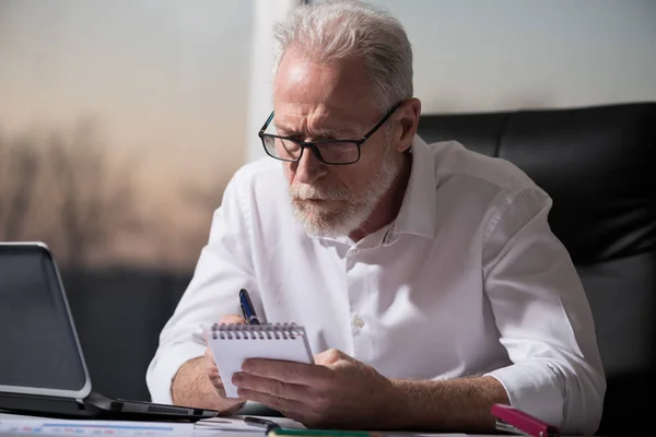 Hombre de negocios senior tomando notas, luz dura — Foto de Stock