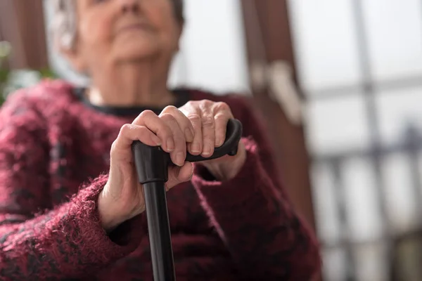 Vieja con las manos en un bastón — Foto de Stock