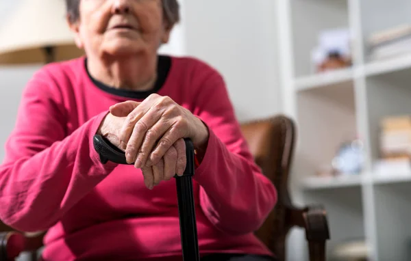 Vieja con las manos en un bastón — Foto de Stock