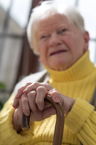 Vieja con las manos en un bastón — Foto de Stock