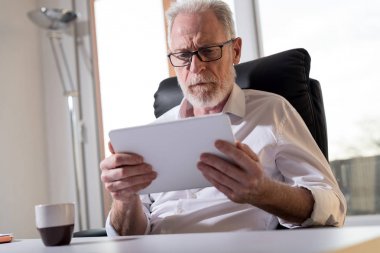 Üst düzey işadamı kullanarak bir dijital tablet, sert ışık