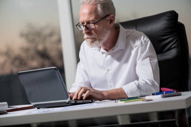 Ofis, sert ışık dizüstü bilgisayar üzerinde çalışan üst düzey iş adamı