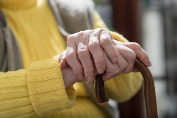 Las manos de anciana sosteniendo un bastón — Foto de Stock