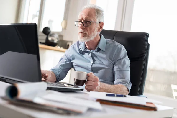 Portret van senior zakenman die op laptop, hard licht werkt — Stockfoto