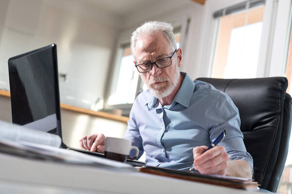 Senior businessman taking notes, hard light