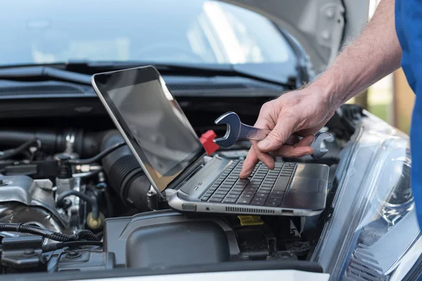 Mecânico usando laptop para verificar o motor do carro — Fotografia de Stock