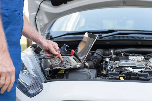 Mecánico usando el ordenador portátil para comprobar el motor del coche — Foto de Stock