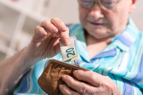 Старшая женщина достает банкноту из бумажника — стоковое фото
