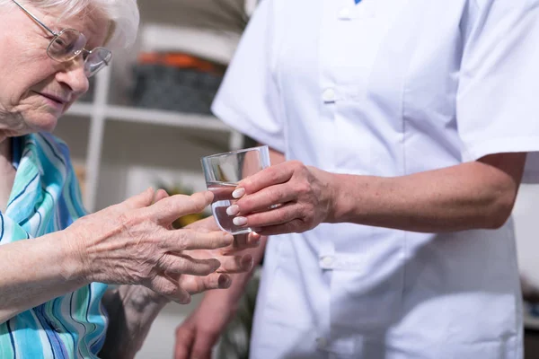 Enfermera dando vaso de agua a la mujer mayor — Foto de Stock