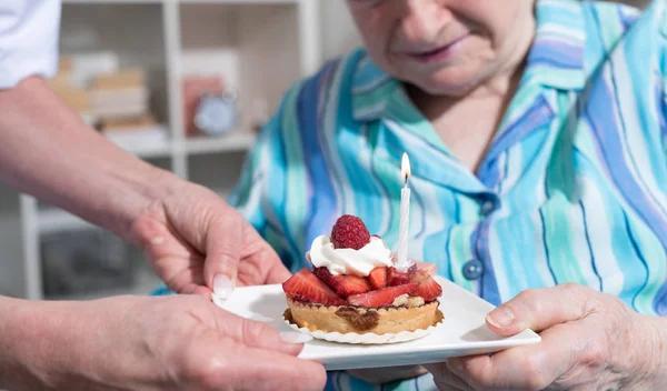 Mujer mayor recibiendo un pequeño pastel de cumpleaños — Foto de Stock