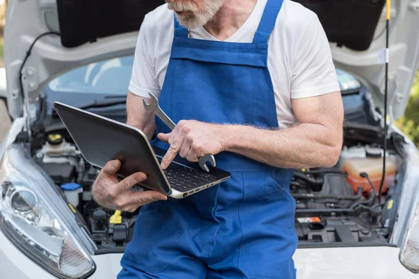 Mecánico usando el ordenador portátil para comprobar el motor del coche — Foto de Stock